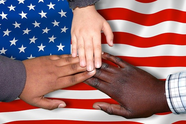 picture of different races touching hands with American flag backdrop